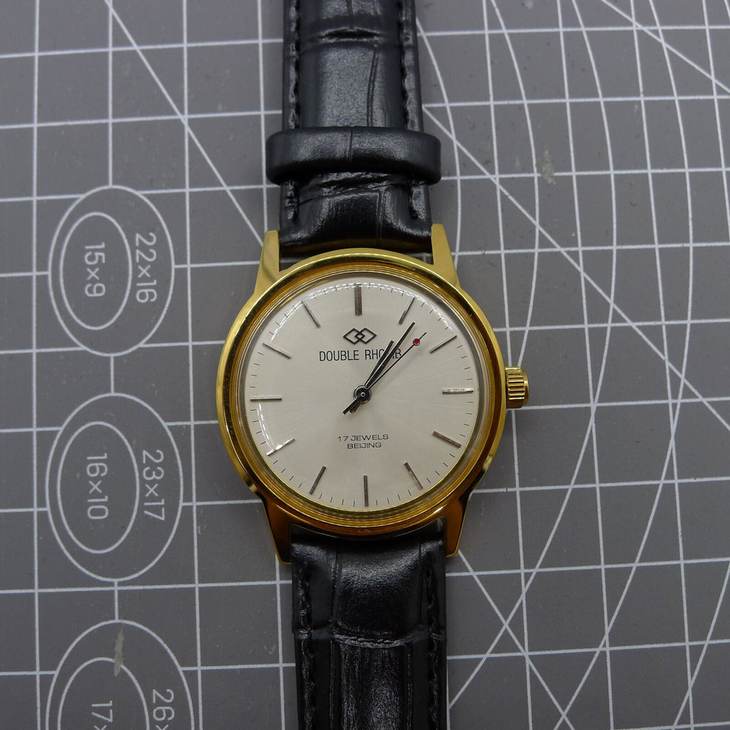 Beijing Double Rhomb watch with golden case, silver nail markers, manual movement, classic style accessory.