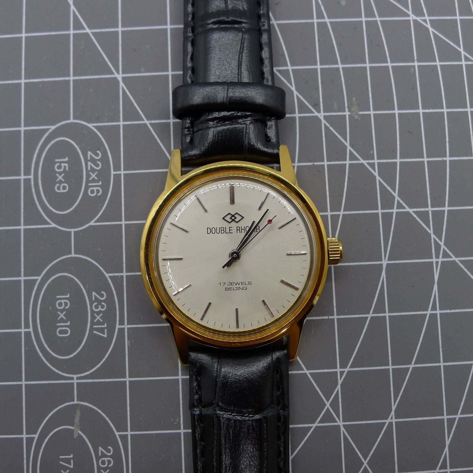 Beijing Double Rhomb watch with golden case, silver nail markers, manual movement, classic style accessory.