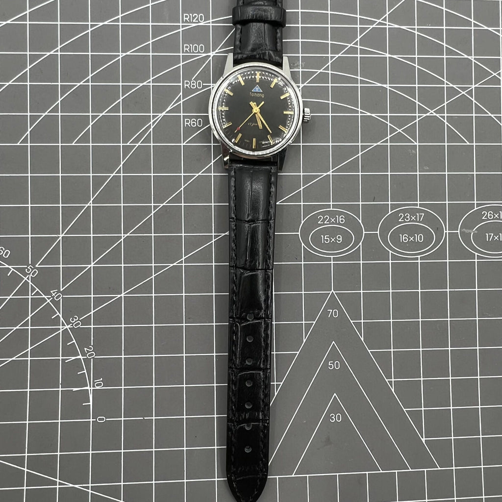 Taihang 32mm manual watch with black dial, golden nail markers, 17 jewels for precise timekeeping.