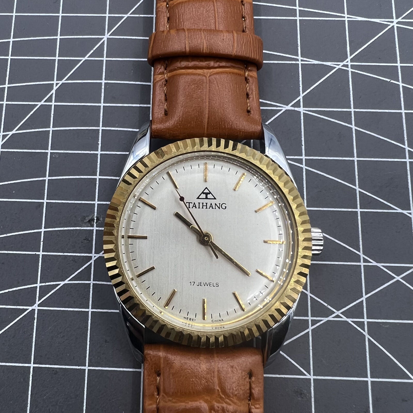 TAIHANG 38mm manual mechanical watch with golden markers, silver dial, round case, and 17 jewels for precise timekeeping.