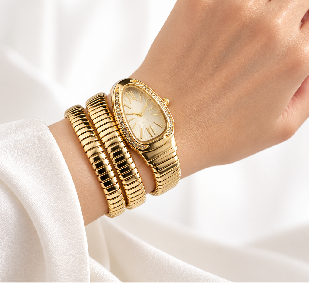 A close-up of a woman's wrist wearing a gold-plated watch with a textured snake-style metal band, layered over a matching gold bracelet, set against a soft white background.