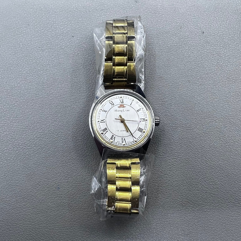 32mm golden stainless steel manual watch with 17 jewels and Roman numeral dial.