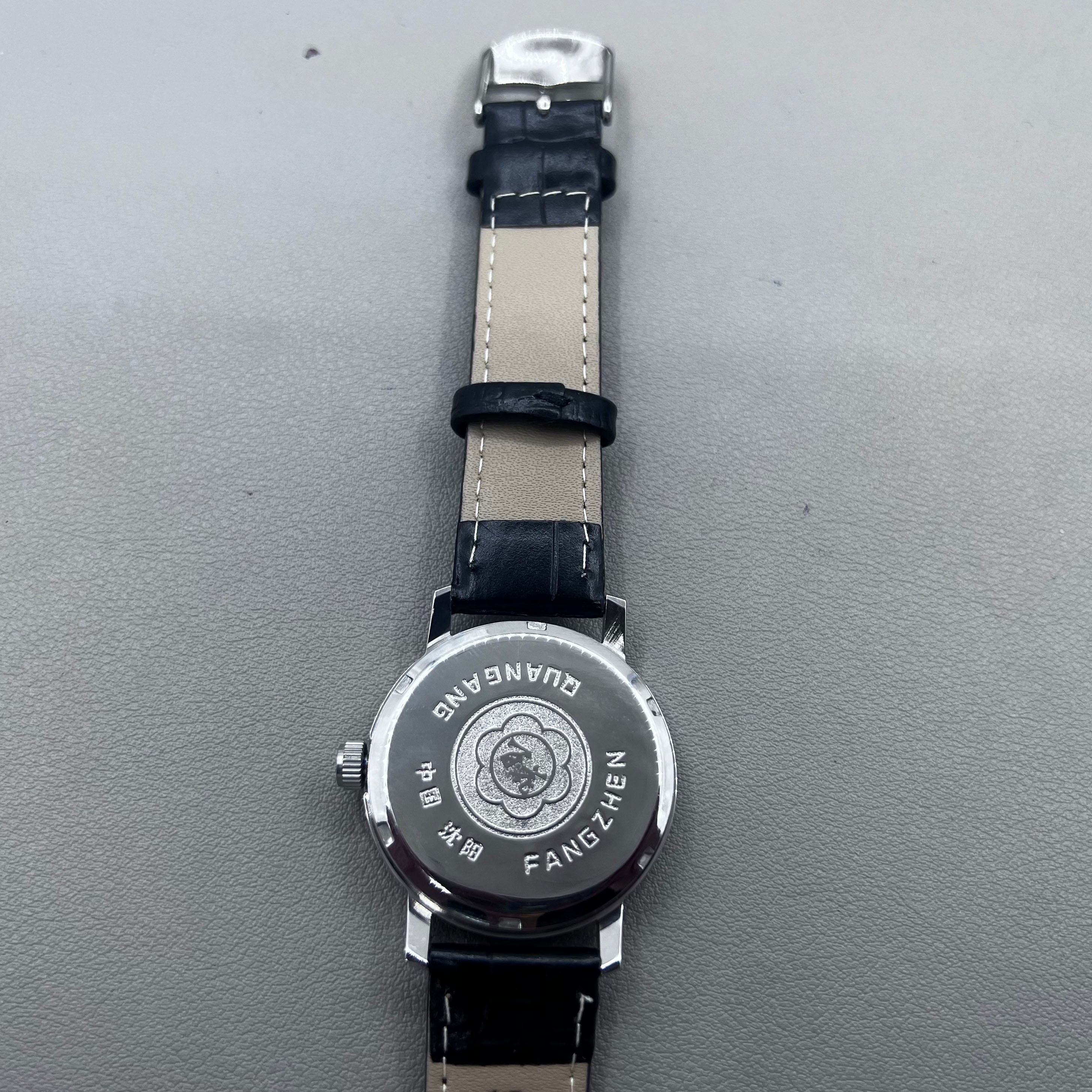 37mm China manual mechanical watch with black strap, silver dial, 19 jewels, shock-resistant design.