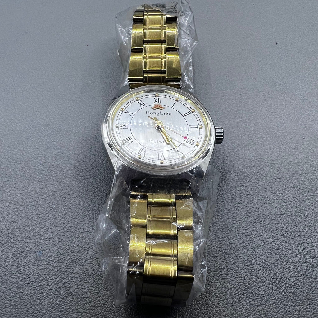 32mm golden stainless steel manual watch with 17 jewels and Roman numeral dial.